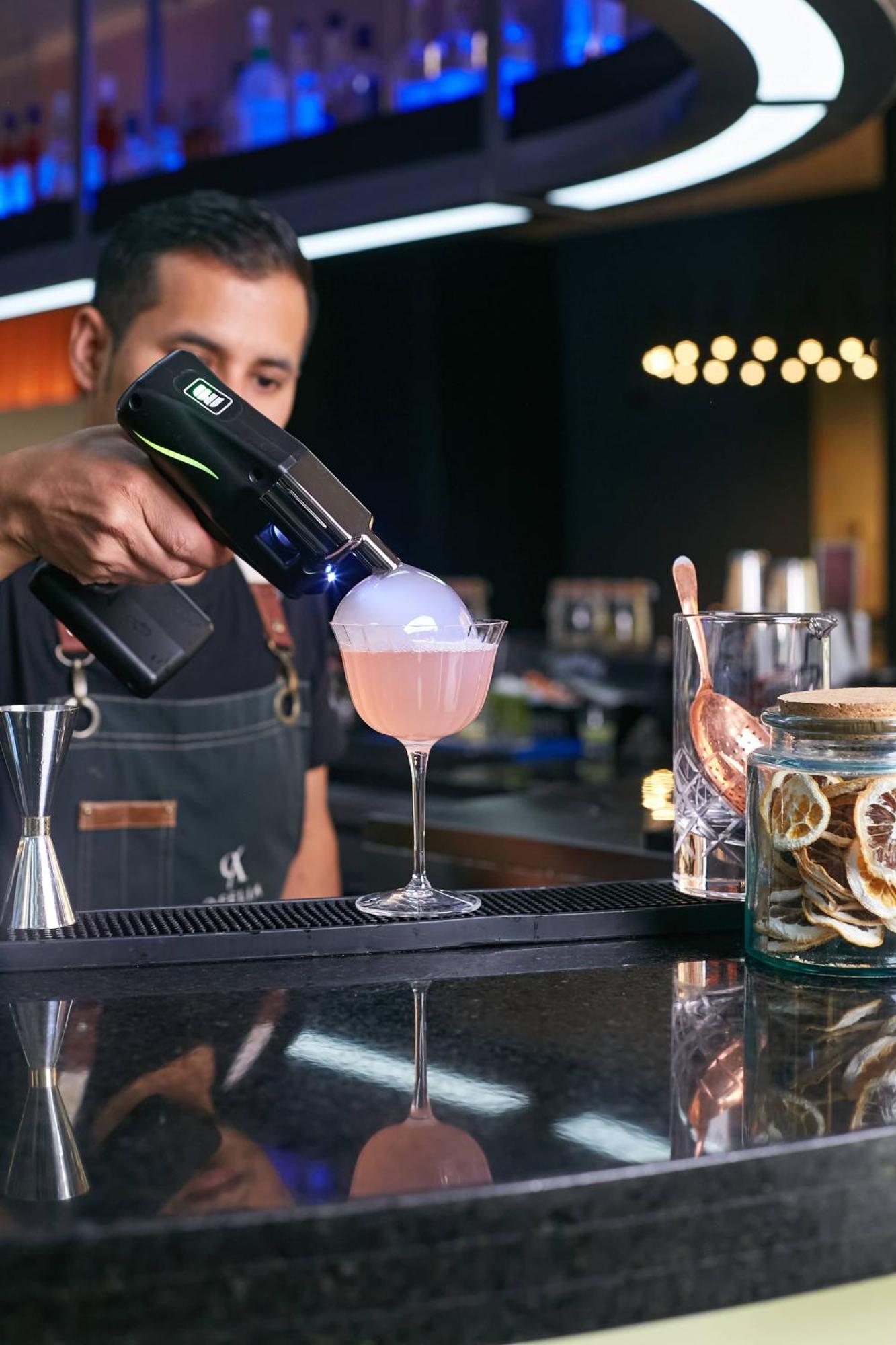 Pullman Santiago Vitacura Ngoại thất bức ảnh A bartender using a blowtorch to cook a cocktail
